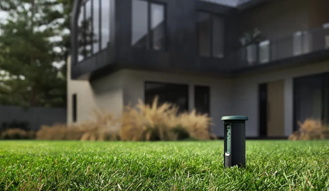 Smart irrigation system controller in a modern backyard with lush green grass.