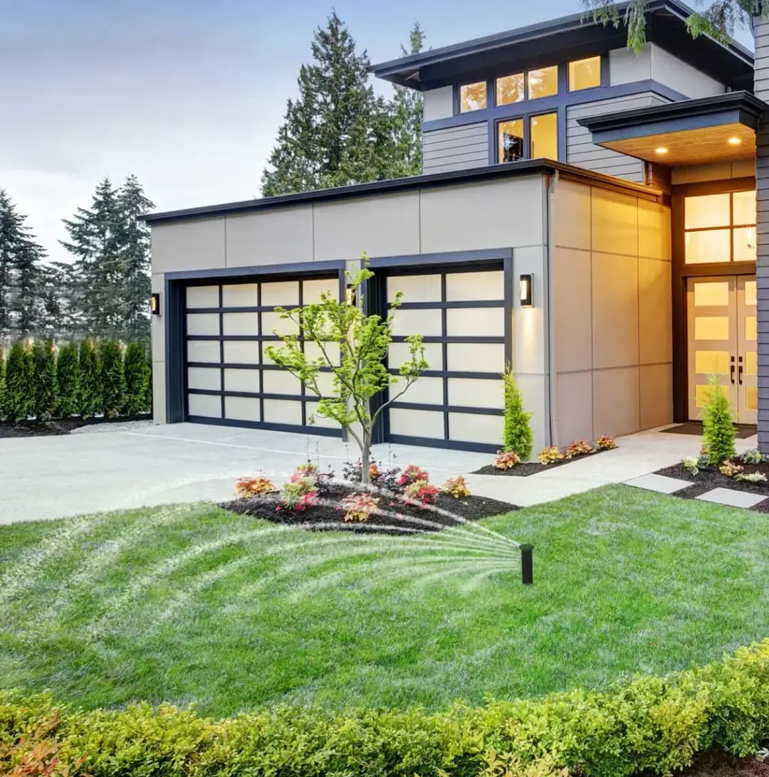 Modern home exterior with lawn sprinkler system and landscaped garden.