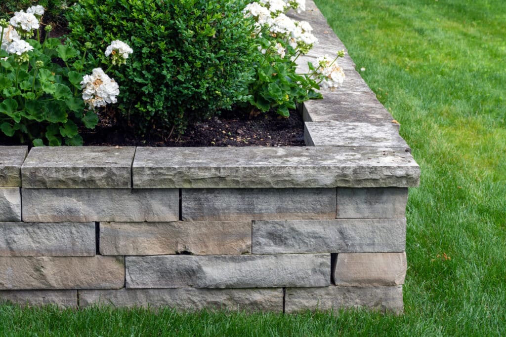 A natural stone retaining wall with matching coping creates a ra