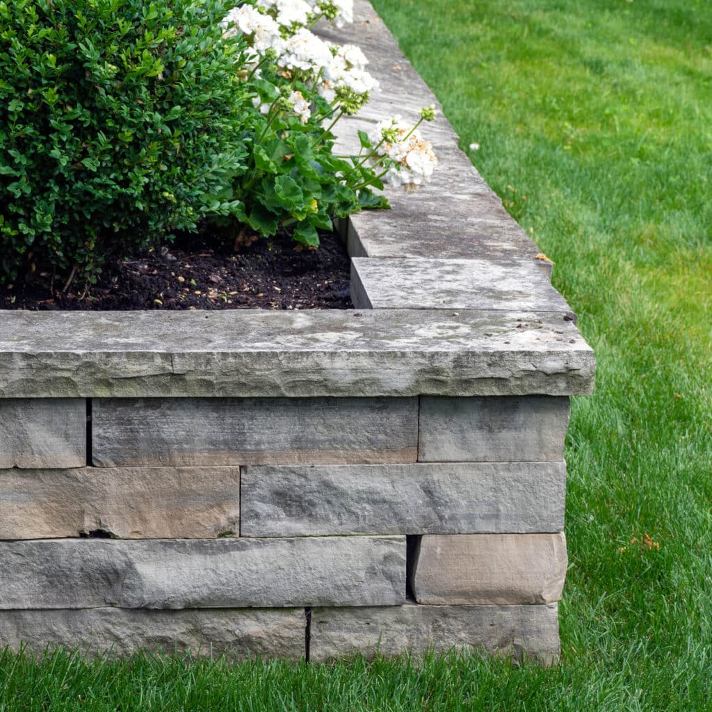 A natural stone retaining wall with matching coping creates a ra